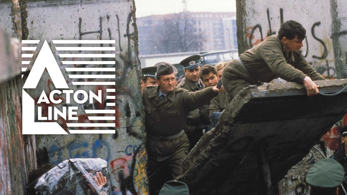 Soldiers climb over a toppled portion of the Berlin Wall in November 1989